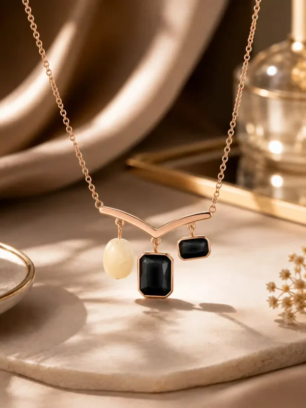 Nazar Grace rose-gold tone pendant necklace with black stones and pearl-inspired white accent on an ivory display