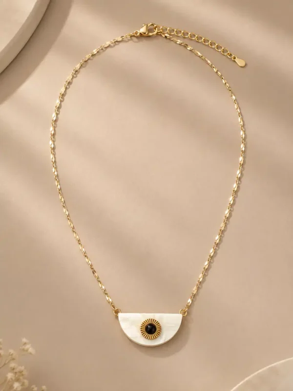 Nivara half-moon evil eye pendant necklace with a white, black and gold-tone design on a faceted chain