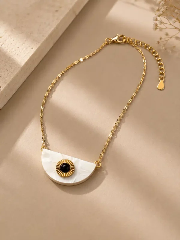 Angled view of Nivara gold-tone evil eye necklace showing the half-moon pendant, lobster clasp and extension chain