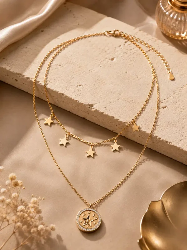 Lunara gold-tone celestial layered necklace with five star charms and a crystal-style medallion on an ivory display