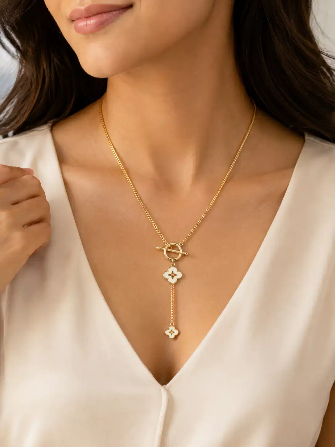 Woman wearing the Fiora gold-tone Y necklace with two ivory flower drops and a white V-neck top