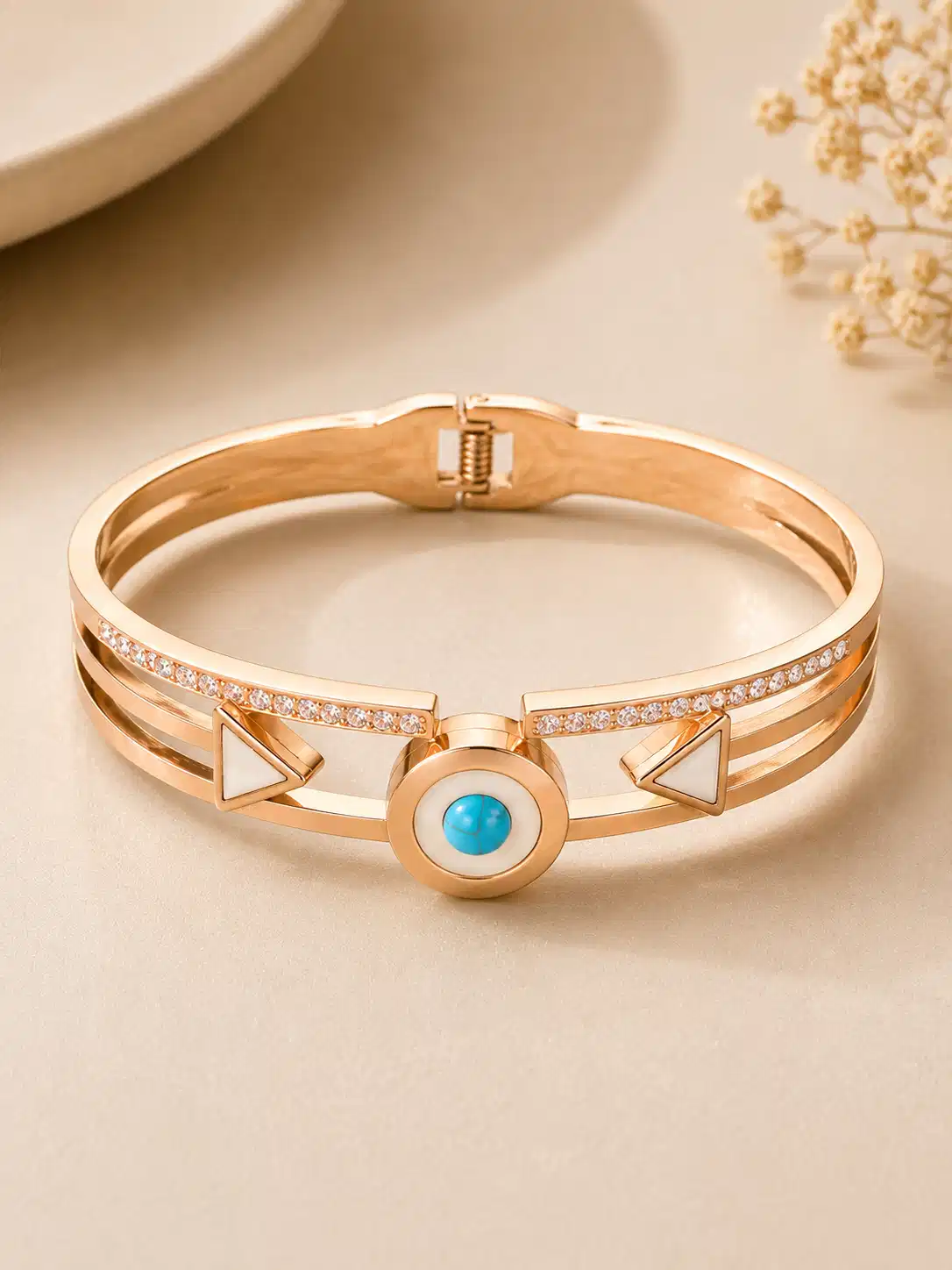 Front view of the Veyra rose-gold-tone bangle with a circular turquoise accent and two ivory triangles