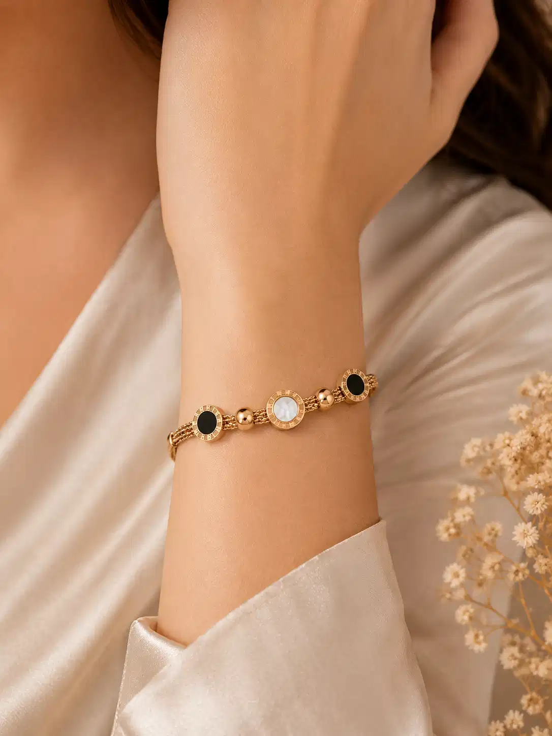 Woman wearing the Mirelle rose-gold multi-strand bracelet with black and ivory circular details