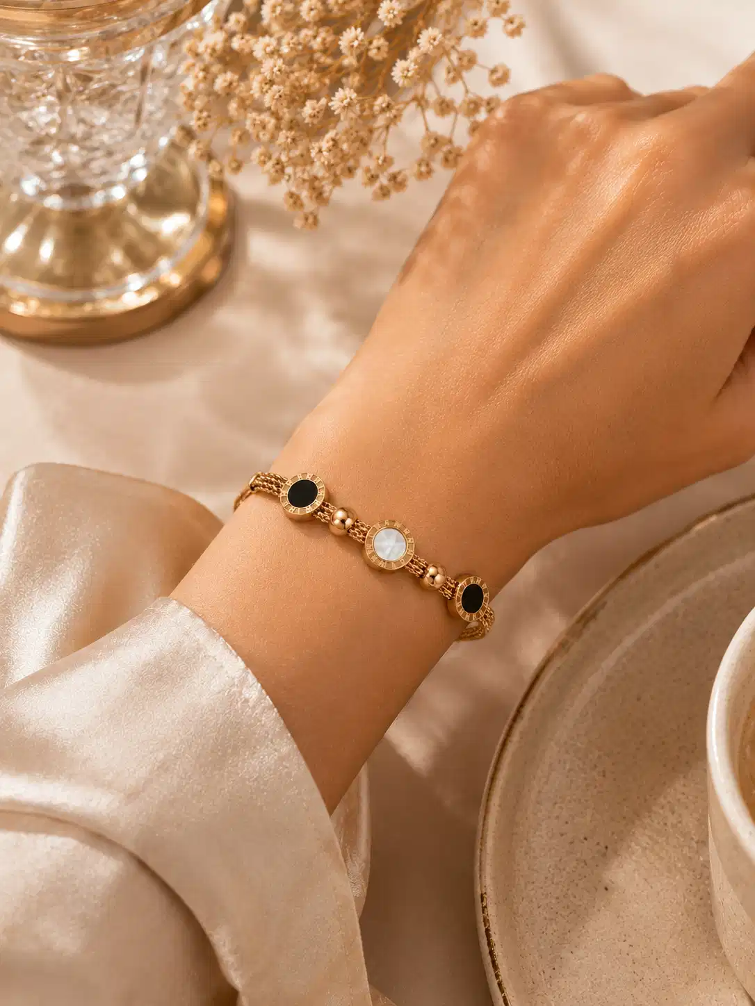 Close wrist view of the Mirelle black and ivory rose-gold-tone bracelet styled with a neutral outfit