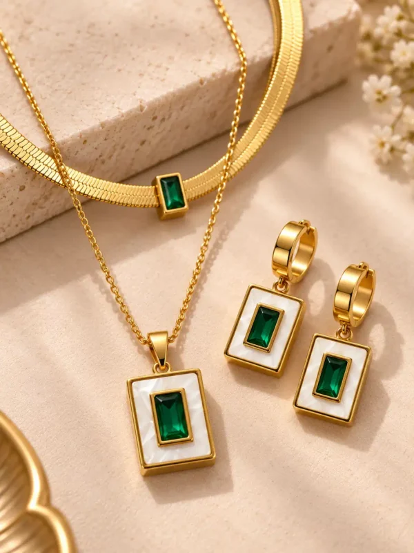 Close-up of gold-tone geometric necklace and earrings with rectangular emerald-green centres and ivory-white frames
