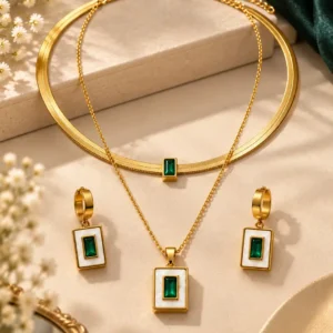 Gold-tone double-layer necklace with emerald-green pendant and matching rectangular drop earrings displayed together