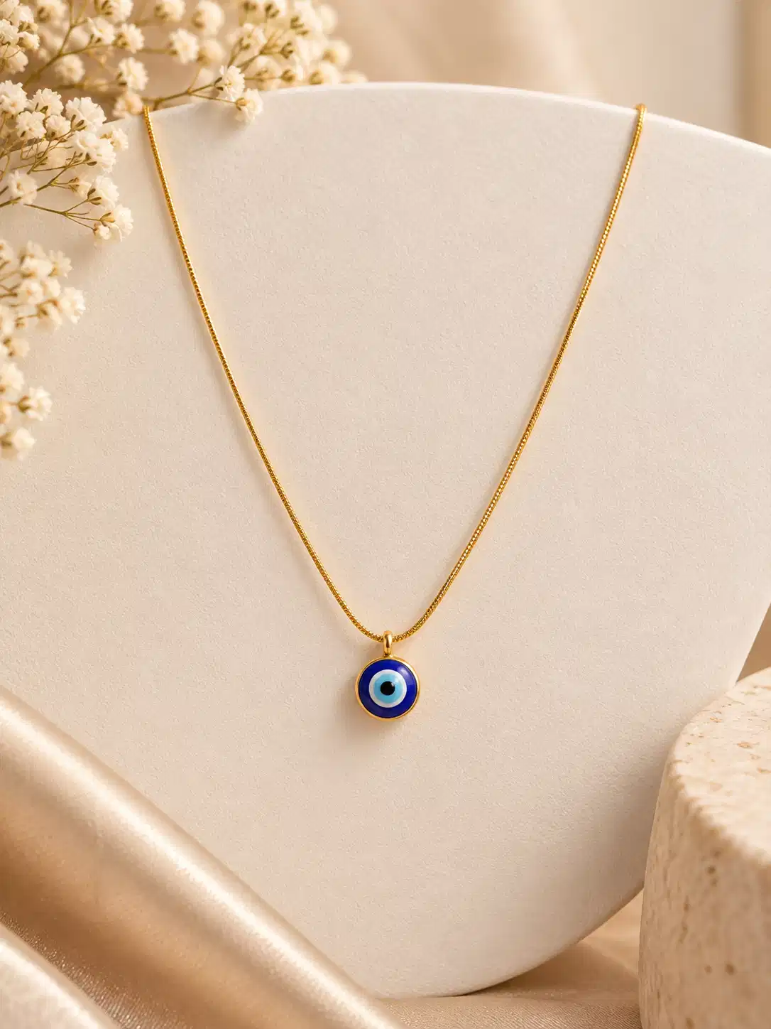 Gold-tone necklace with round blue evil eye pendant featuring white, sky-blue and black concentric details