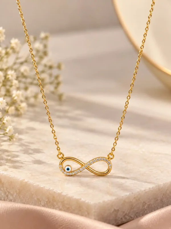 Gold-tone infinity necklace with clear crystal-style accents and a small blue evil-eye detail