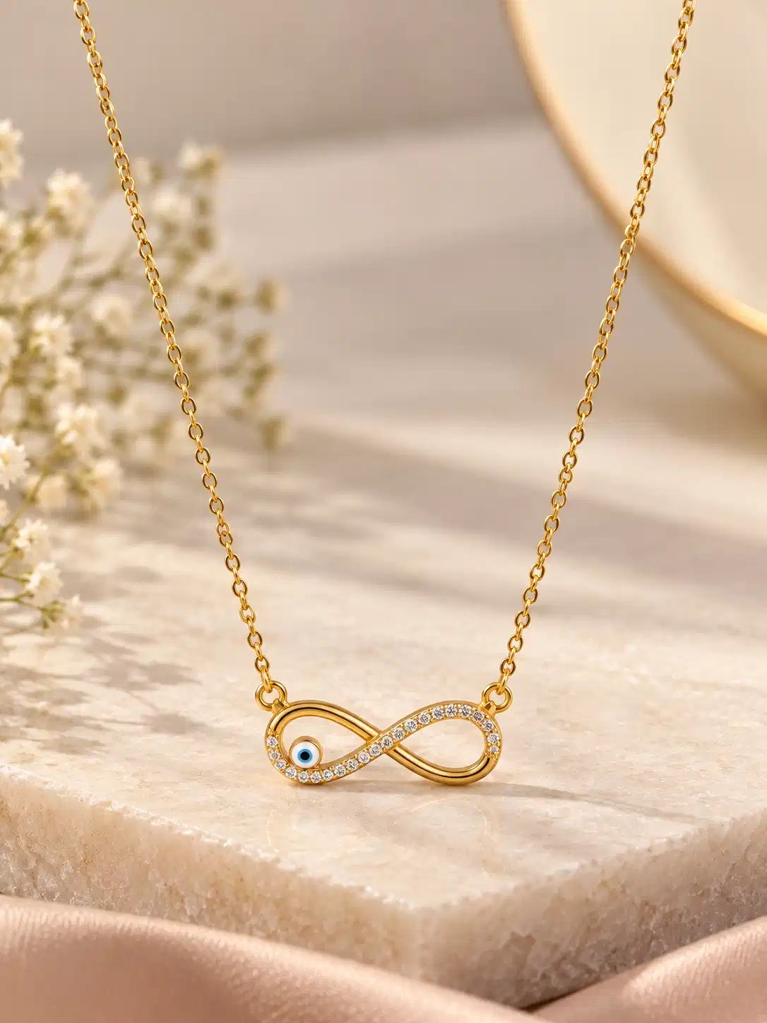 Gold-tone infinity necklace with clear crystal-style accents and a small blue evil-eye detail