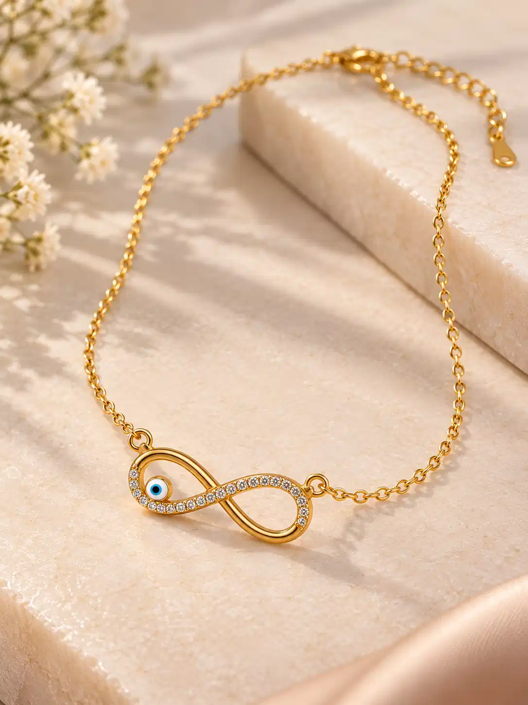Gold-tone infinity nazar necklace laid flat with fine chain, lobster clasp and extension links