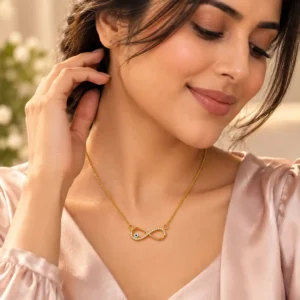 Woman wearing a gold-tone infinity nazar necklace with a soft blush pink V-neck outfit