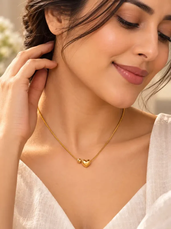 Woman wearing minimal gold-tone heart necklace with white V-neck outfit for everyday styling
