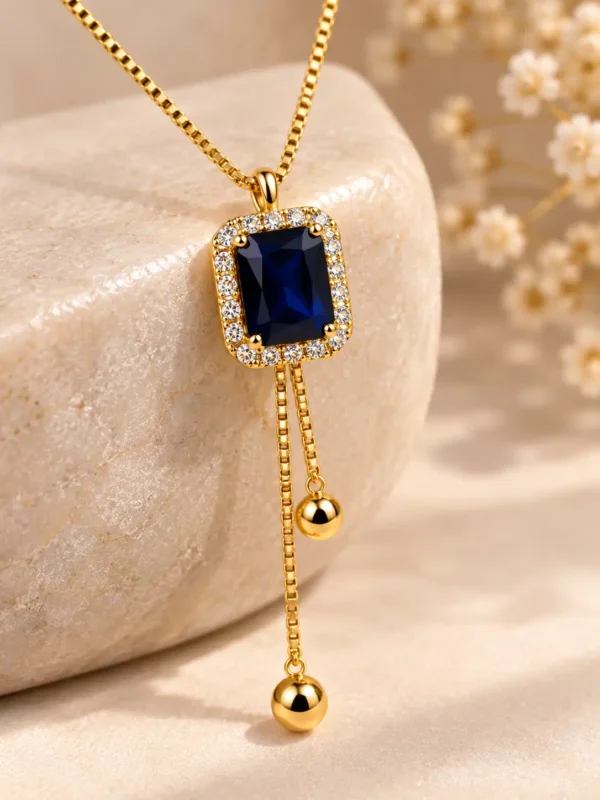 Close-up of deep blue rectangular stone with clear crystal halo and gold-tone drops on Blue Hour Y-Drop Necklace
