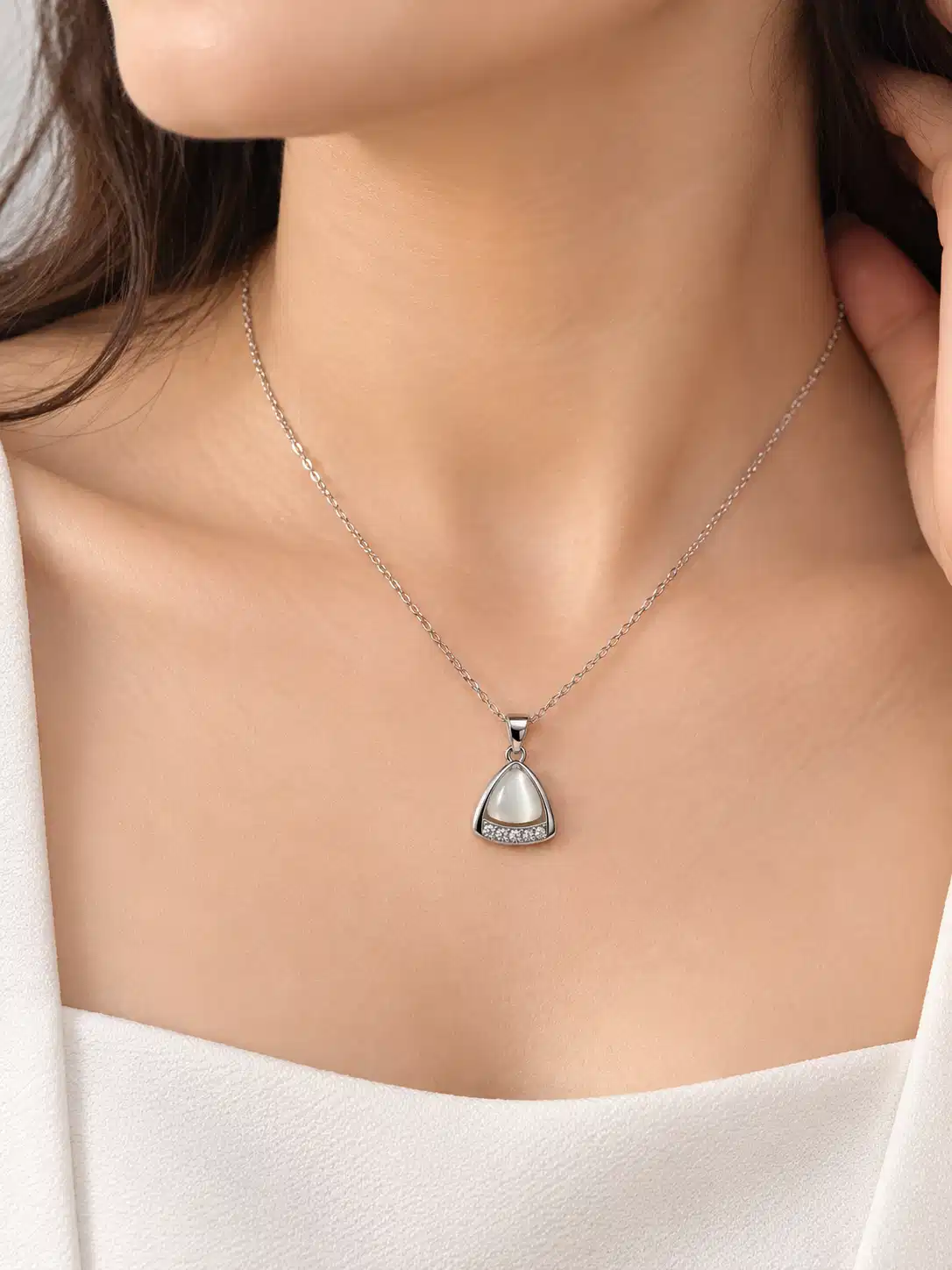 Woman wearing Ivory Glow silver triangle pendant necklace with white outfit for a minimal everyday look