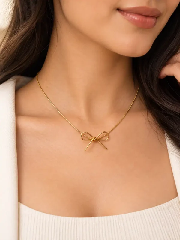 Woman wearing a minimal gold bow necklace with a white top for elegant everyday and office styling.