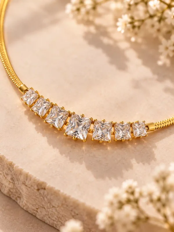 Close-up of seven graduated square-cut clear stones set on a polished gold-tone necklace