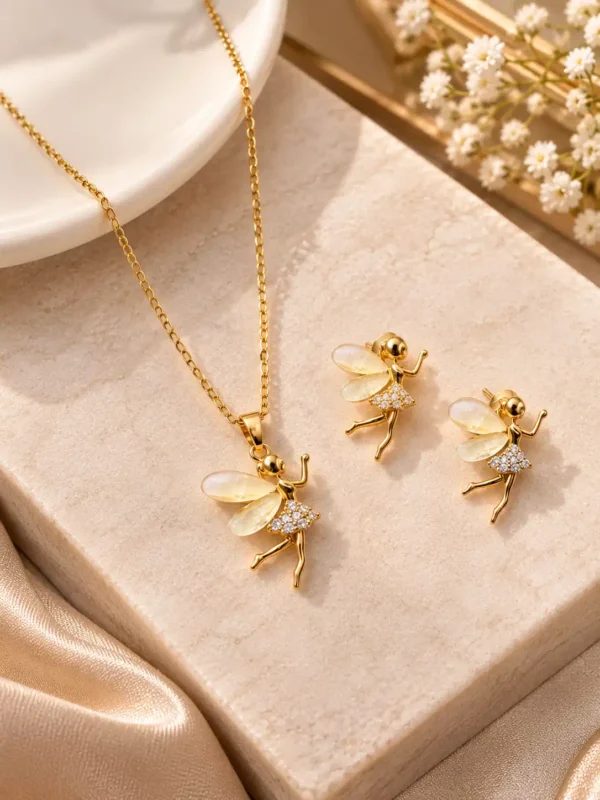 Gold tone fairy necklace and matching earrings with ivory translucent wings displayed on a neutral jewellery surface