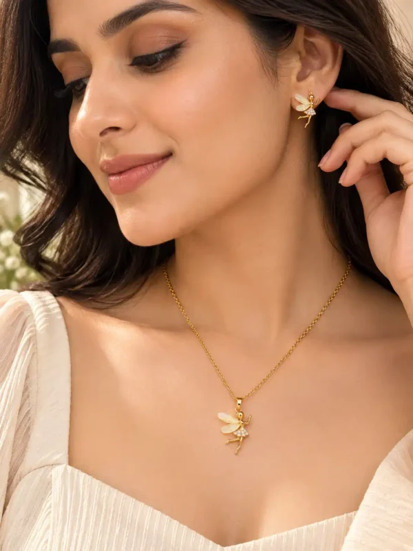 Woman wearing Aurelia gold tone fairy pendant necklace and matching fairy earrings with an ivory outfit