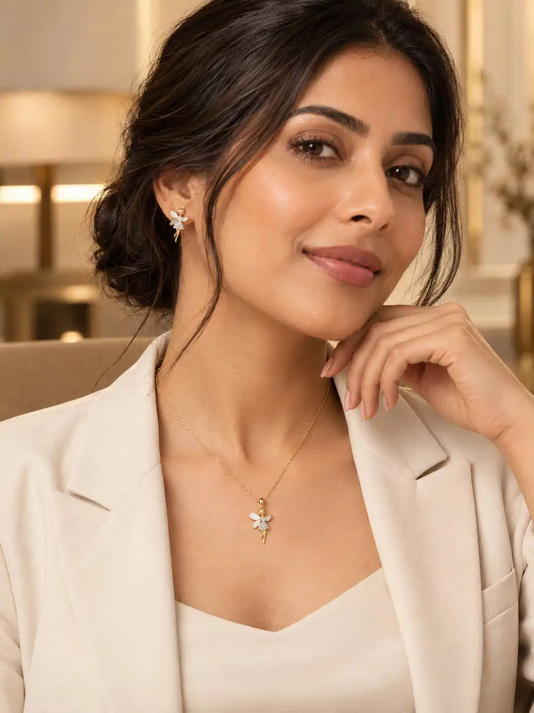 Woman styling Aurelia gold fairy necklace and matching ivory wing earrings with a white blazer