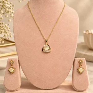 Ivora Glow gold-tone pendant and earring set with ivory centre and crystal accents displayed on a blush jewellery stand