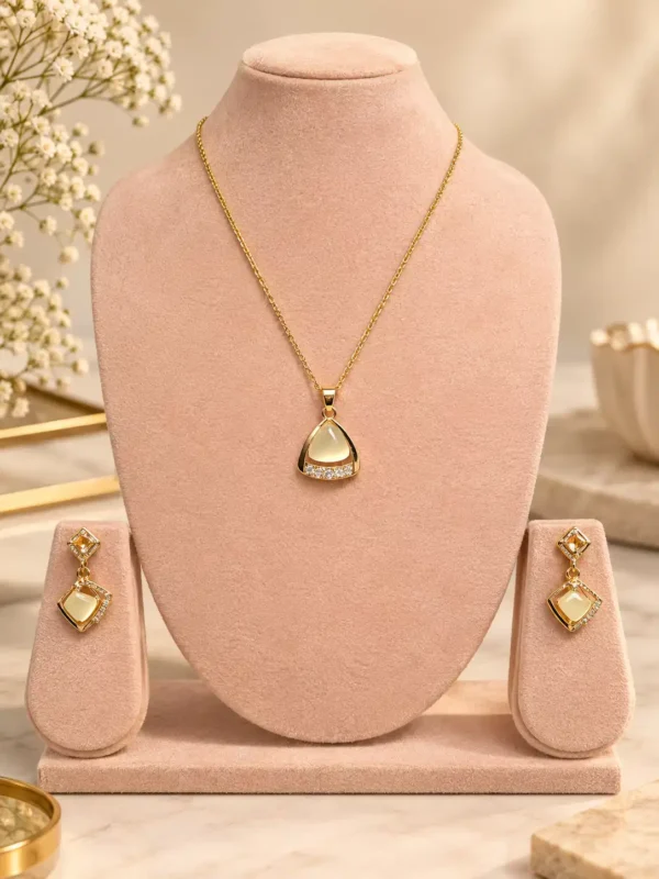 Ivora Glow gold-tone pendant and earring set with ivory centre and crystal accents displayed on a blush jewellery stand