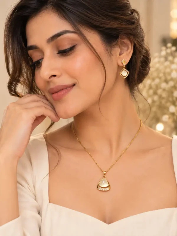 Woman styling an elegant gold pendant necklace and matching ivory geometric earrings for a refined feminine look