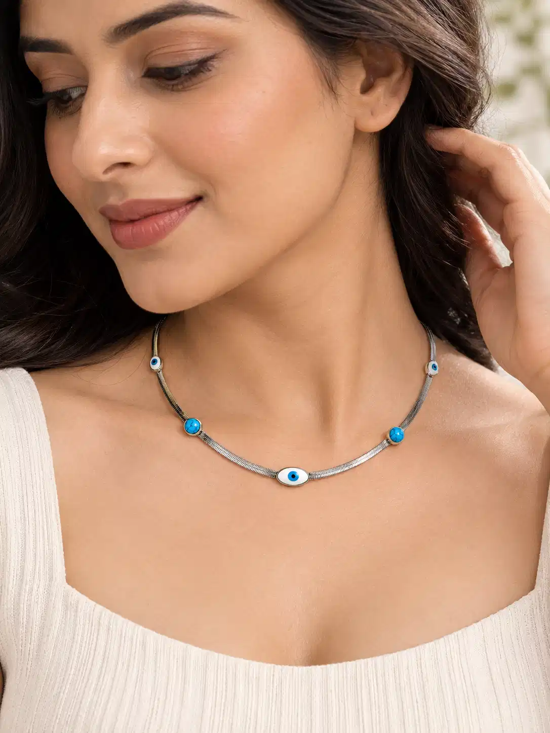 Woman wearing silver evil eye necklace with turquoise accents and white square-neck top