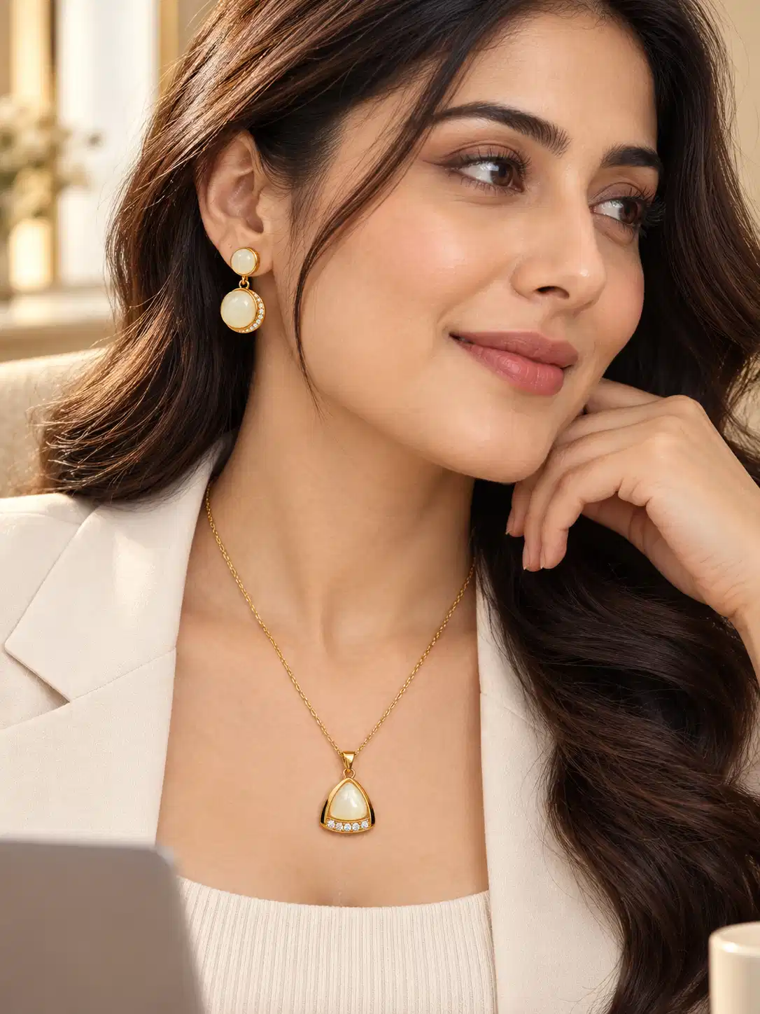 Woman wearing gold-tone ivory pendant and matching earrings with white blazer for office wear