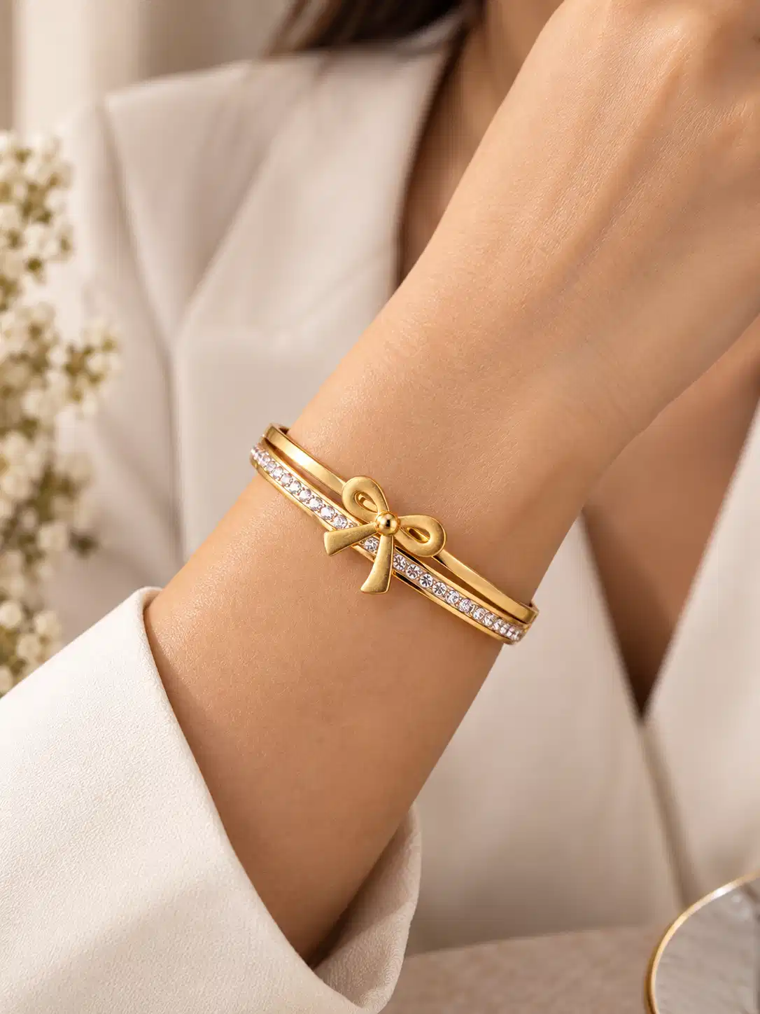 Woman wearing gold crystal bow bangle with white outfit for elegant everyday styling