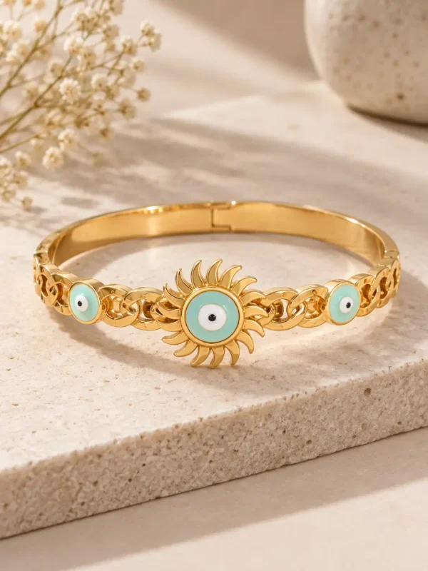Gold-tone Solara Sunburst Evil Eye bangle for women with a large turquoise nazar centre and two smaller evil-eye motifs.