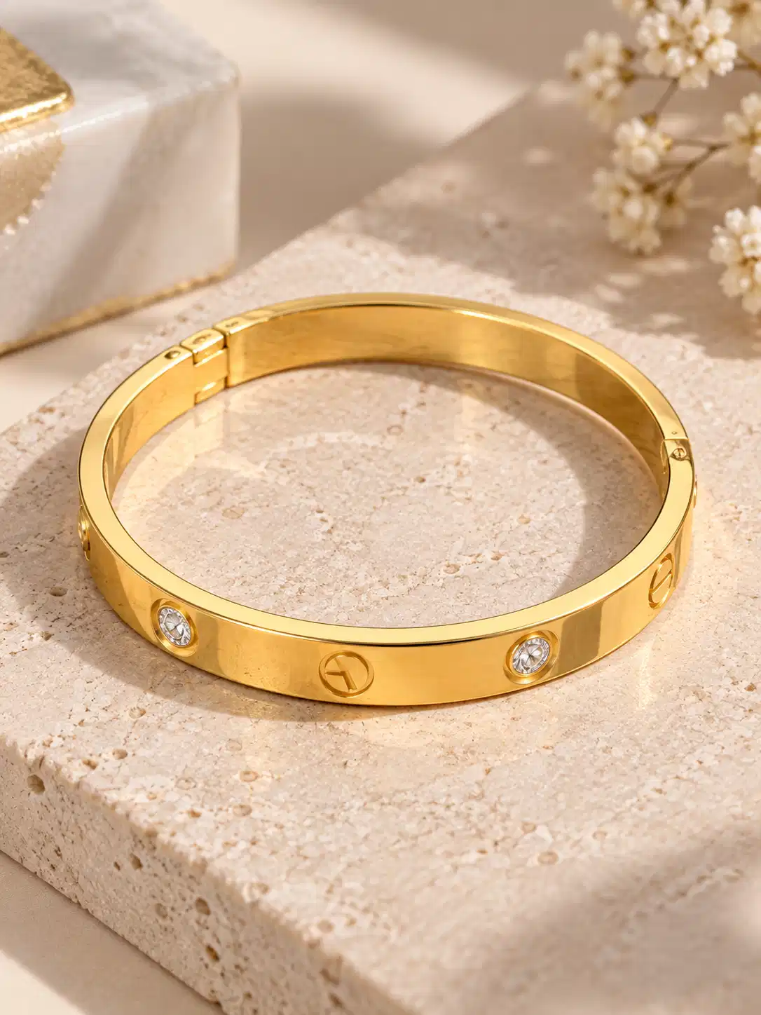 Full view of Aurelia structured gold bracelet with spaced clear crystals, screw motifs and hinged closure for women.
