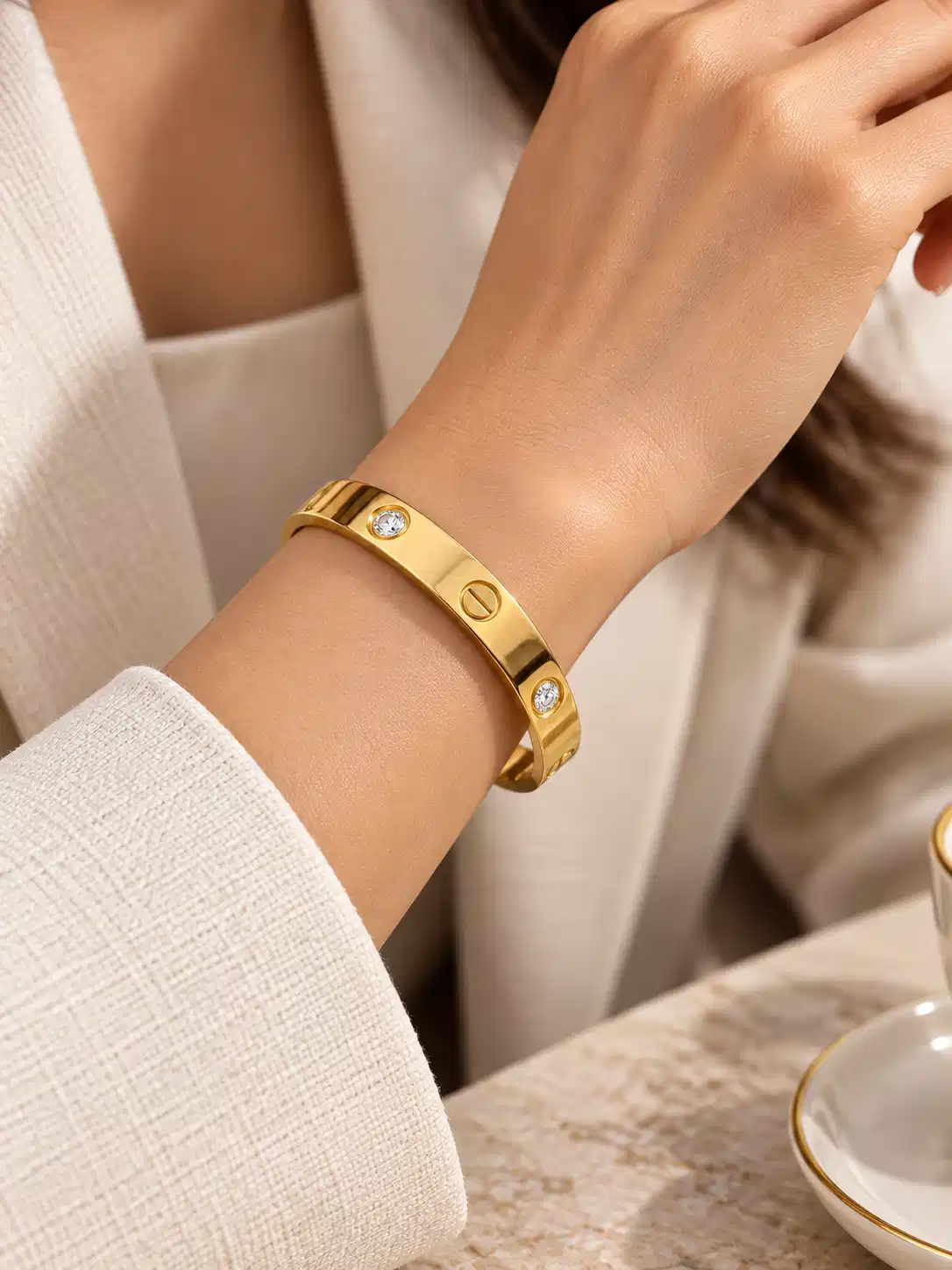 Woman wearing Aurelia minimal gold crystal bangle with white office outfit for polished everyday wrist styling.
