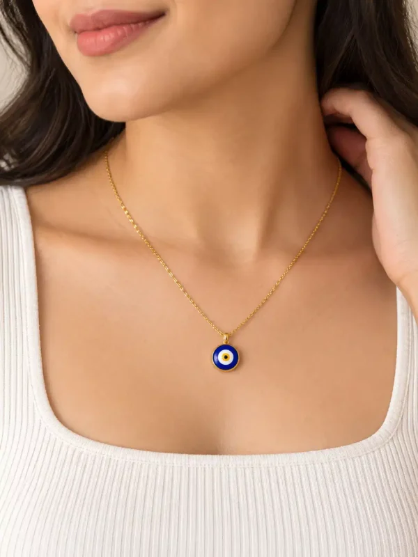 Woman wearing a minimal gold-tone blue evil eye pendant necklace with white square-neck top