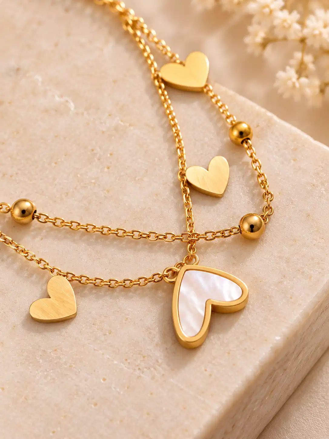 Close-up of gold and ivory heart charms on Amora layered bracelet for women