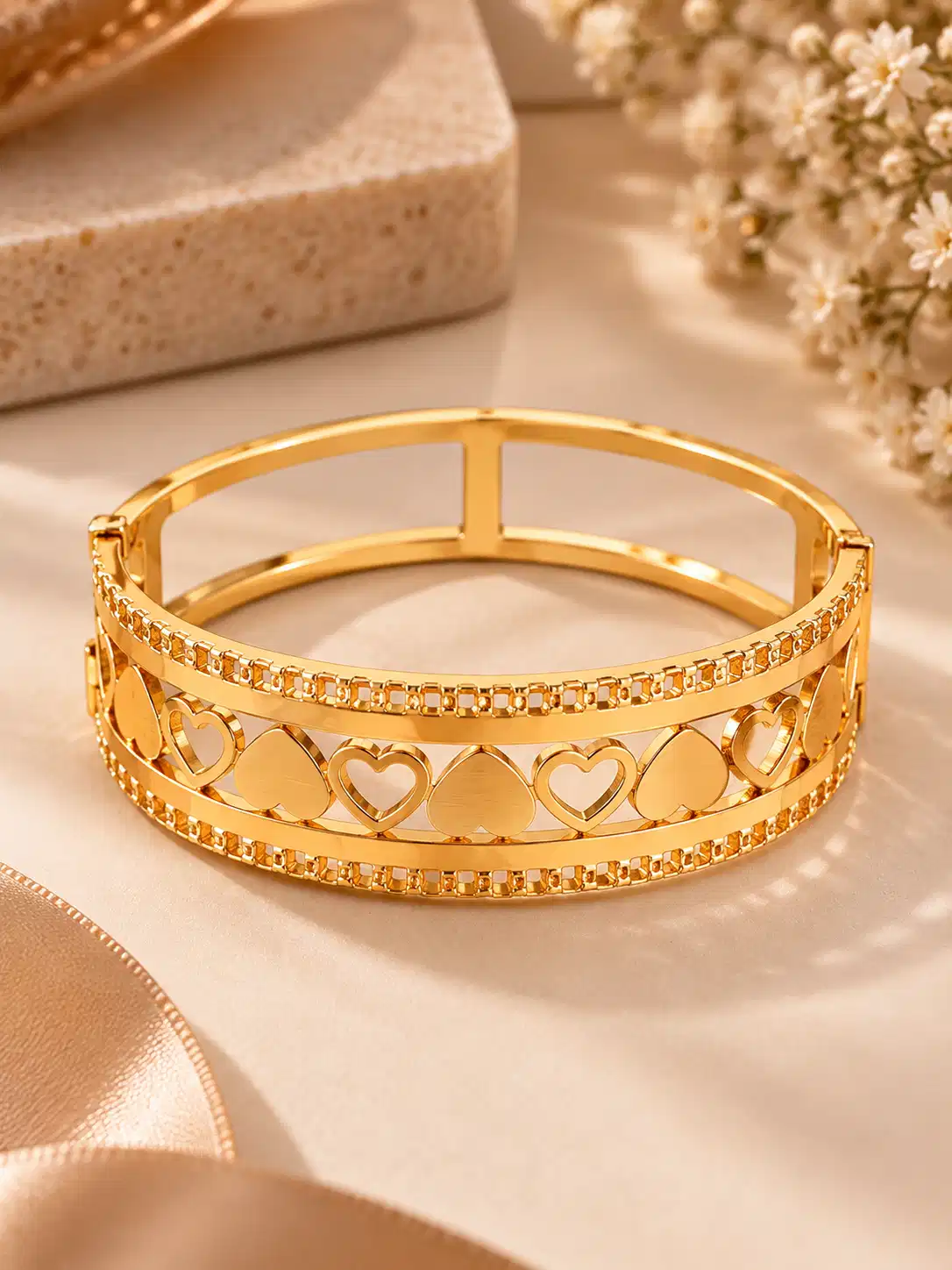 Front view of wide gold heart bangle for women with open and solid heart lattice design