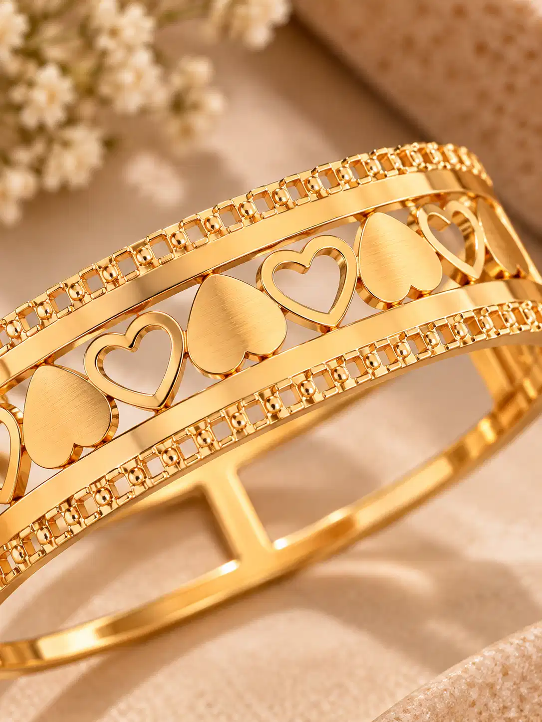 Close-up of alternating solid and open hearts on Amora gold statement bangle