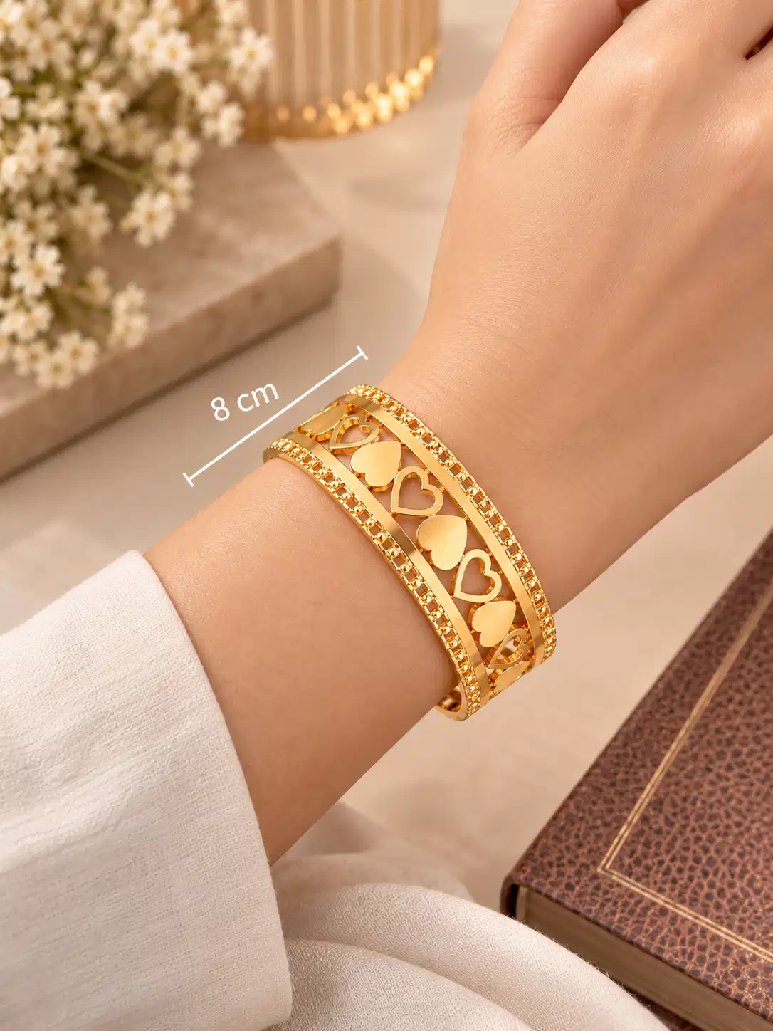 Amora 8 cm gold heart statement bangle shown on a womanโs wrist