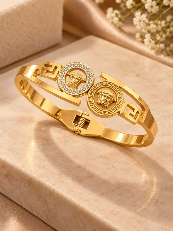 Angled view of gold twin medallion rigid bangle with crystal halo, engraved detailing and spring hinge